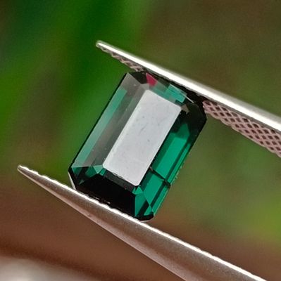 a close up of a green stone being held by a pair of pliers