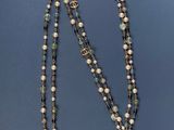 a close up of a necklace with pearls and a cross on it