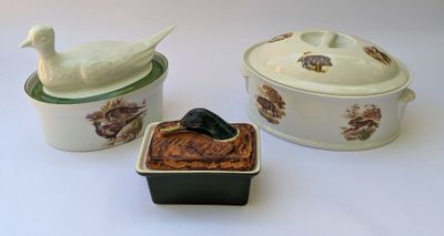 a white bird sitting on top of a bowl next to a black and white container