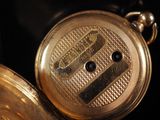a close up of a gold pocket watch on a black background