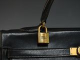 black leather handbag with a padlock on a grey background