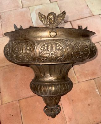 un oiseau en bronze posé sur un socle, sur un sol en briques