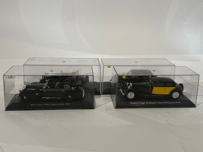 deux modèles réduits de voitures noirs et jaunes, présentés dans des vitrines transparentes posées sur un fond blanc