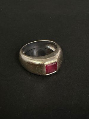 un gros plan d'une bague en argent sertie d'une pierre rouge