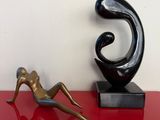 statue d'une femme allongée sur une table rouge, à côté d'une sculpture représentant une femme