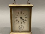 a small brass clock with roman numerals on the face