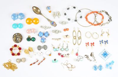 de nombreuses paires de boucles d'oreilles et de bracelets disposées sur une surface blanche