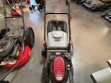 La tondeuse à gazon est garée dans le garage, avec d'autres tondeuses à gazon en arrière-plan.