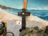 une peinture représentant une croix sur le mur, à côté d'un tas de pierres