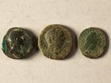 Trois pièces de monnaie romaines antiques sont représentées sur un fond blanc.