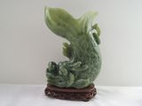 une statue verte représentant un poisson, posée sur un socle en bois