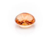a close up of a faceted orange sapphire stone on a white background