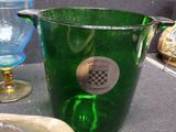 a green glass pitcher sitting on a table next to a blue glass