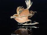 gold plated brooch depicting a bird with a bow and arrow in its beak