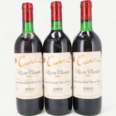 three bottles of red wine sitting next to each other on a white surface