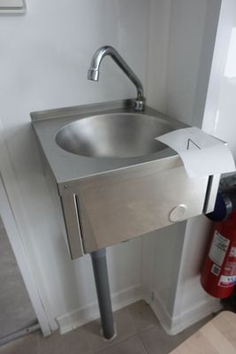 un lavabo situé dans un coin de la salle de bains, équipé d'un distributeur de serviettes en papier