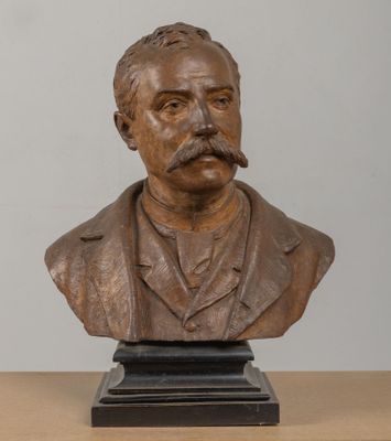 statue représentant le buste d'un homme moustachu, posée sur une table en bois