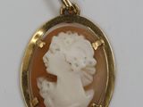 un gros plan sur un pendentif plaqué or orné d'un camée représentant une femme