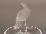 a glass bird sitting on top of a glass plate