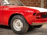 a red and white car parked in front of a brick wall
