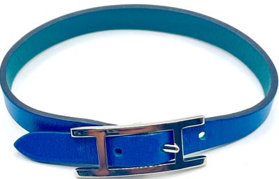 une ceinture en cuir bleu avec une boucle argentée sur fond blanc