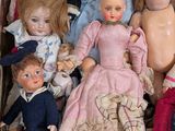 a bunch of dolls sitting in a suitcase on the floor