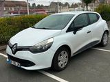 une voiture blanche garée sur un parking, à côté d'une haie