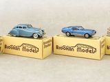 quatre petites voitures posées sur des cartons, sur une surface blanche
