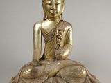 une statue en or représentant un Bouddha assis sur un rocher