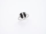 une image représentant une bague noire et blanche posée sur une surface blanche