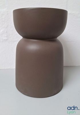 un vase marron posé sur une table blanche