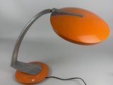 an orange desk lamp on a white surface with a black cord