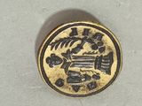 a gold coin with a design on it on a white surface