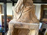 a stone sculpture of a woman sitting on a bench