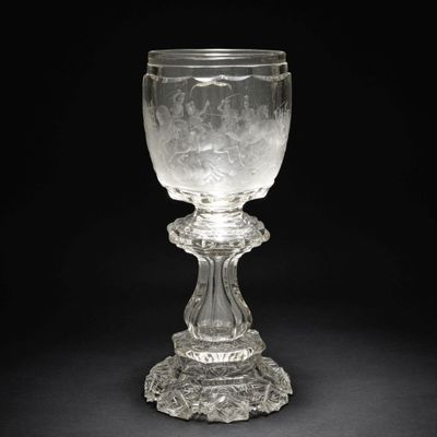 un gobelet en verre posé sur un socle, sur fond noir