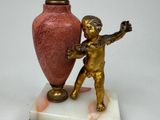 a statue of a boy holding a vase on a marble base