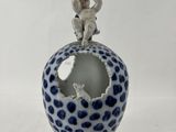 une petite figurine posée sur un vase bleu et blanc