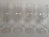 six verres à vin vides alignés sur une surface blanche