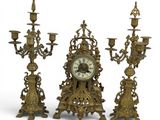 three candlesticks and a clock on a white background