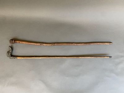 deux bâtons en bois auxquels sont suspendues des chaînes, posés sur une surface blanche