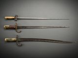 three old swords are displayed on a gray surface with a black background