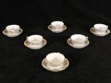 six tasses et soucoupes sont disposées en cercle sur un fond noir