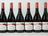 six bouteilles de vin rouge sont alignées sur une table