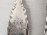 a silver spoon and a spoon with a monogram on it