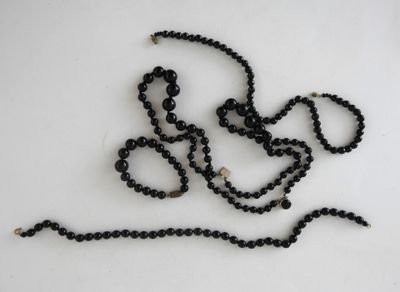 a close up of a black beaded necklace on a white surface