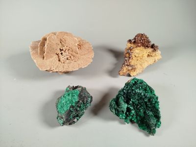three pieces of green and brown mineral sitting on a white surface