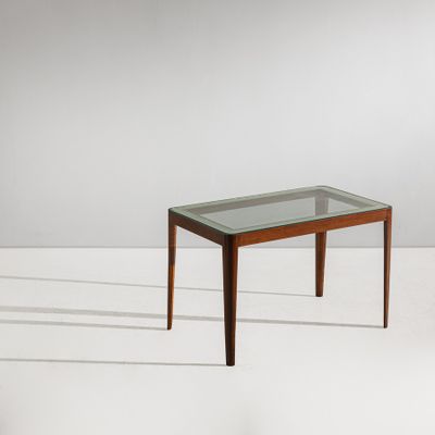 une table basse avec un plateau en verre et des pieds en bois