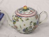 a teapot with a lid sitting next to a book