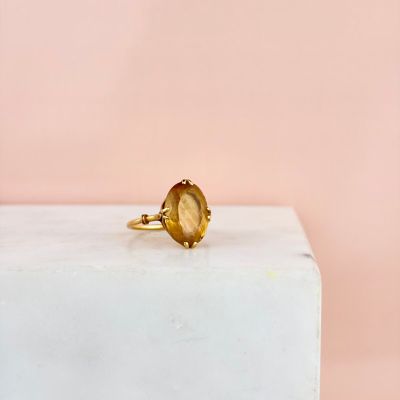 a close up of a ring with a yellow stone on top of a white block