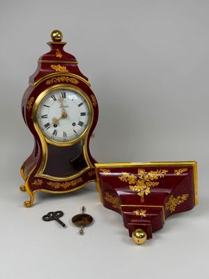une horloge rouge et dorée posée à côté d'une tasse